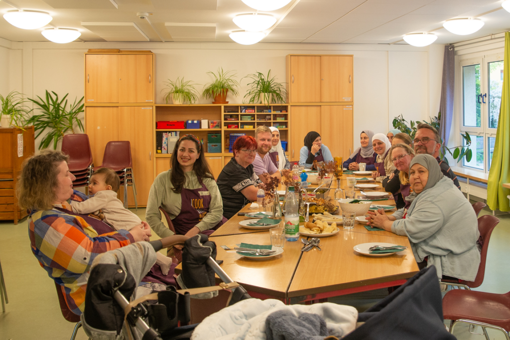 Köche und Gäste an einem reichlich gedecktem Tisch