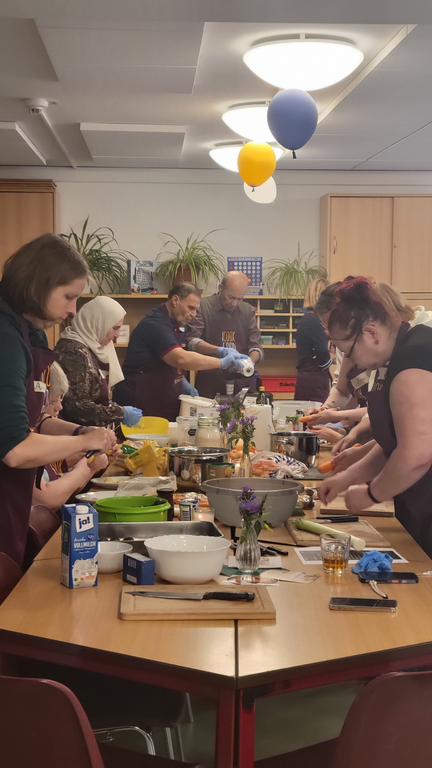 Mehrere Personen stehen um den Tisch und bereiten verschiedene Speisen zu