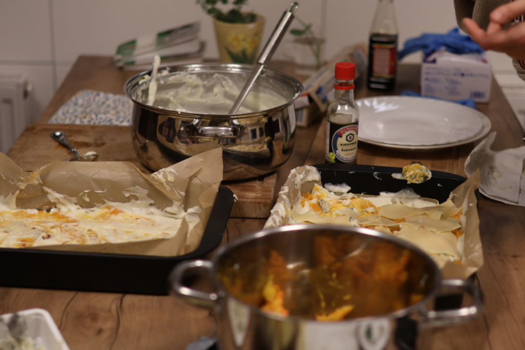 Auf dem Küchentisch sind die Zutaten und Geschirr für die Zubereitung der Lasagne
