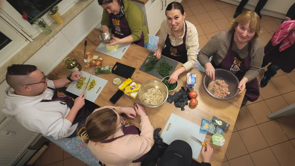Mehrere Personen bereiten am Küchentisch eine Vorspreise zu