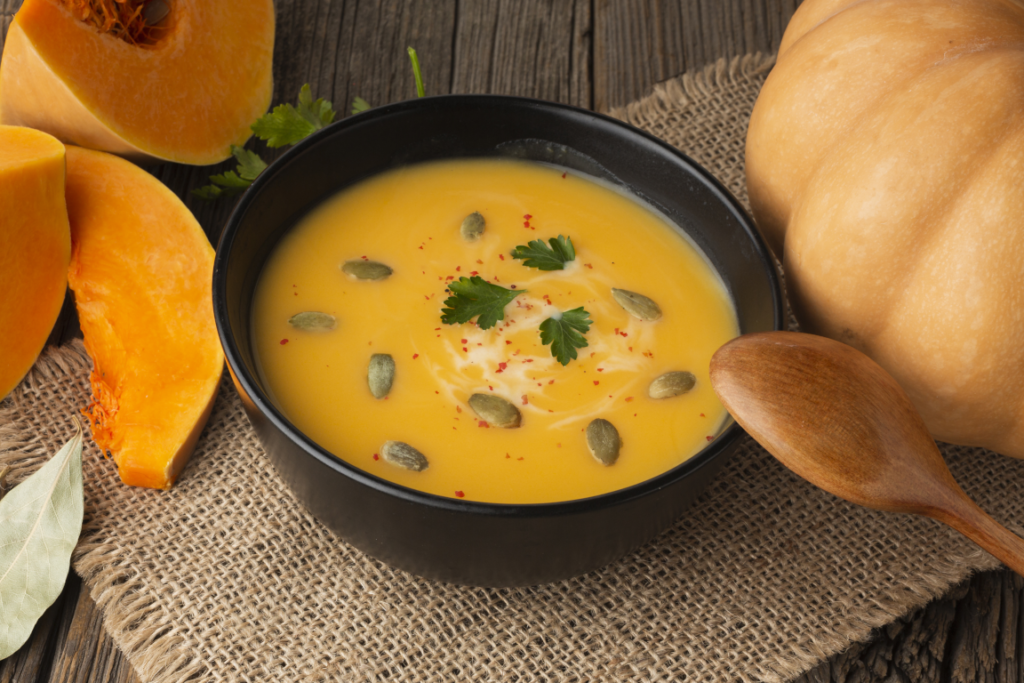 Kürbissuppe in einer schwarzen Schale garniert mit Kürbiskernen